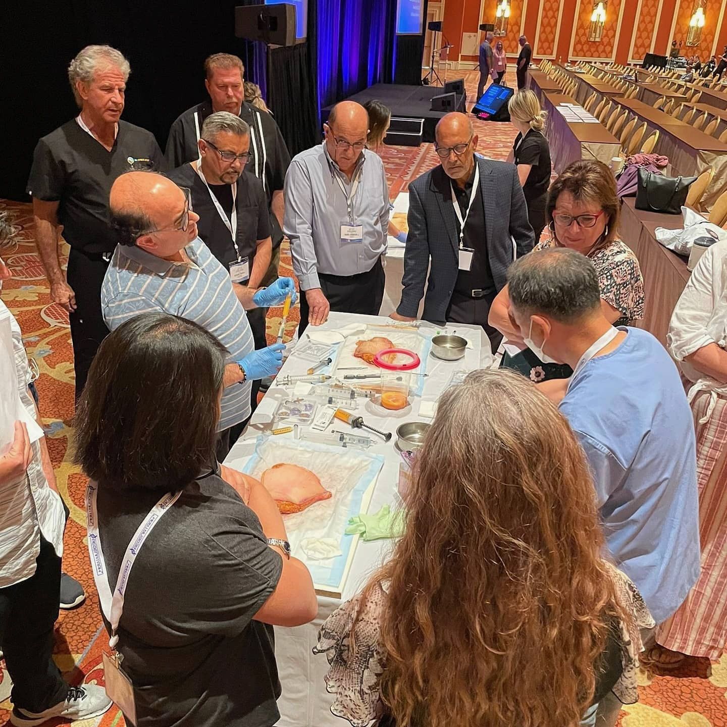 Copcu in surgical gloves demonstrating tissue processing to delegates around a workshop table
