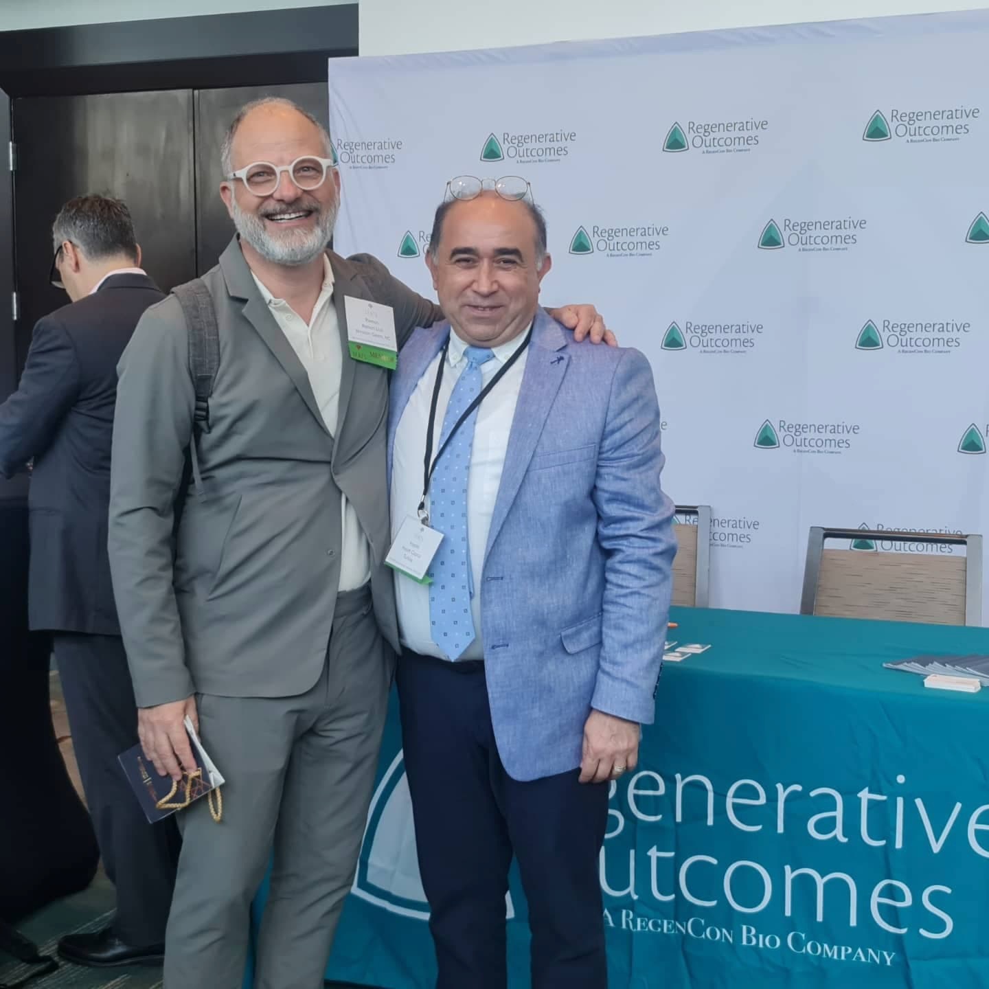 Copcu with a colleague in front of a Regenerative Outcomes exhibitor backdrop
