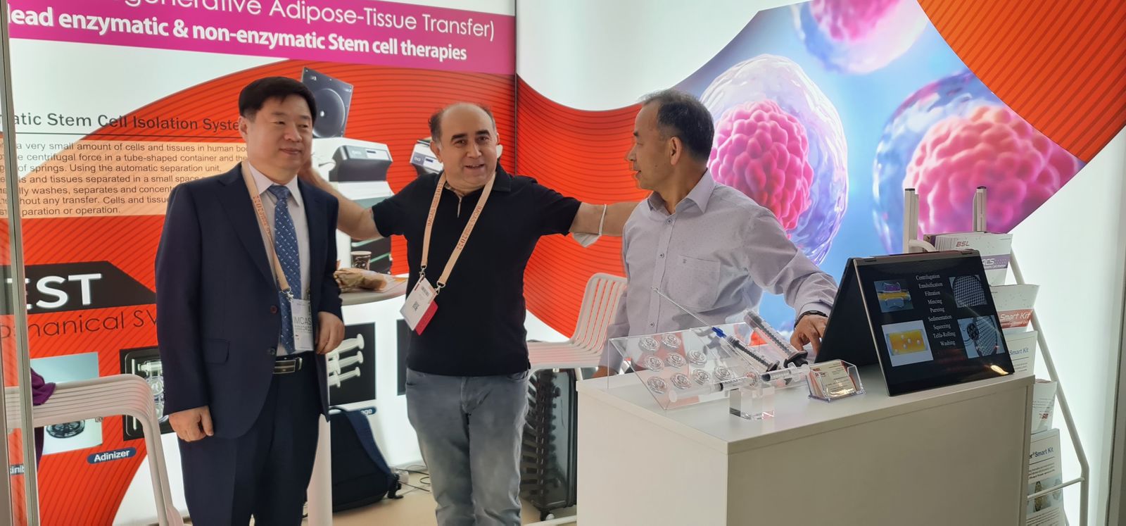 Copcu with colleagues at the MEST exhibition booth, backed by a banner for non-enzymatic stem cell therapies