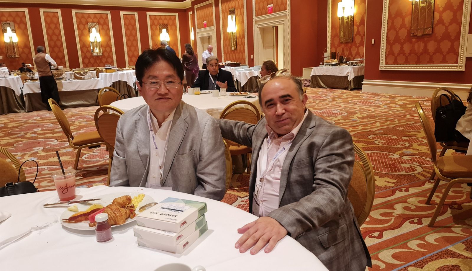 Copcu seated with a colleague at a conference breakfast table
