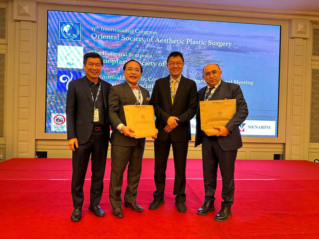 Copcu on stage with three colleagues holding presentation gifts at the 17th International Congress of the Oriental Society of Aesthetic Plastic Surgery