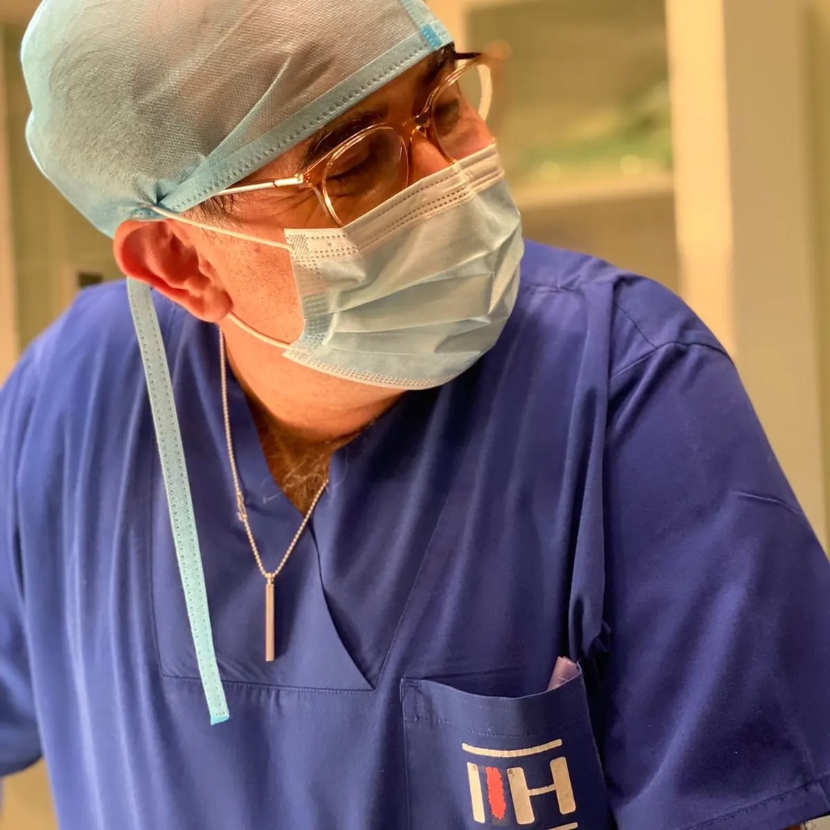 Prof. Copcu in surgical cap, mask and scrubs, operating